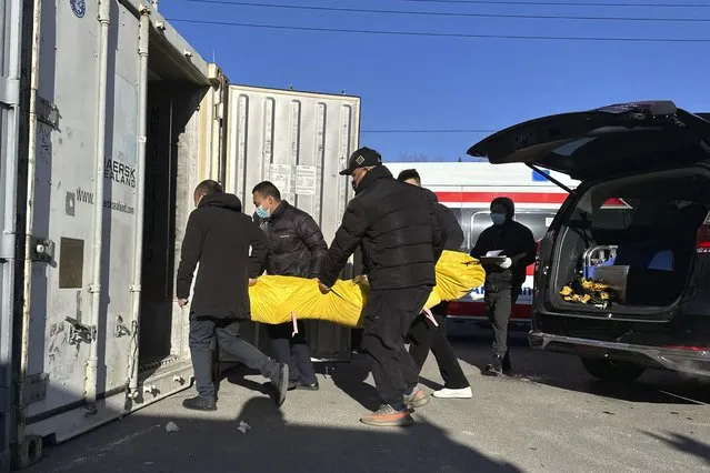 Workers transfer a body into a container for storage at a crematorium in Beijing, Saturday, December 17, 2022. Deaths linked to the coronavirus are appearing in Beijing after weeks of China reporting no fatalities, even as the country is seeing a surge of cases. (Photo by Ng Han Guan/AP Photo)