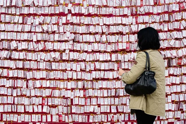 A Buddhist woman places a handwritten note on display as prayers take place at the Jogyesa Buddhist temple for the success of children who at the same time were sitting for the annual nine-hour college entrance exam, locally known as “Suneung”, in Seoul on November 17, 2022. South Korea closed its airspace to ensure silence and offered police escorts for tardy test takers on November 17 as more than half a million students sat high-stakes college admission exams. (Photo by Anthony Wallace/AFP Photo)