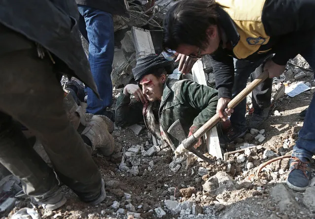 Volunteers from the Syrian Civil Defence (known as the White Helmets) dig a man out of the rubble following an air strike on Saqba, in the besieged rebel-held Eastern Ghouta area near Damascus, on January 9, 2018. Air strikes and artillery fire killed over a dozen civilians in a besieged rebel enclave near Damascus targeted by near-daily regime bombardment, a war monitor said. (Photo by Abdulmonam Eassa/AFP Photo)