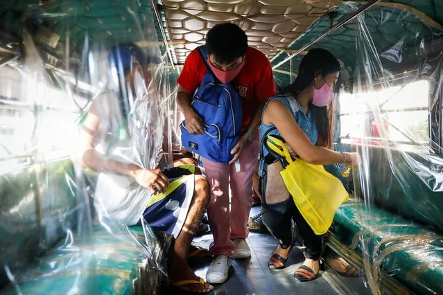 A passenger wearing a mask for protection against the coronavirus disease (COVID-19) boards the jeepney, while another sprays disinfectant on her seat, in Quezon City, Metro Manila, Philippines, July 3, 2020. (Photo by Eloisa Lopez/Reuters)