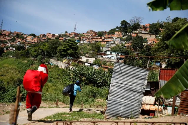 A man dressed as Santa Claus walks through the southern general cemetery to hand out toys to children in a low-income neighborhood, in Caracas, Venezuela on December 17, 2022. (Photo by Leonardo Fernandez Viloria/Reuters)