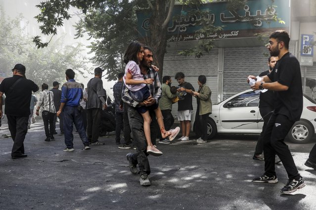 A man carries a wounded girl after an explosion in downtown Tehran amid Israel's three-day campaign of strikes against Iran, Sunday, June 15, 2025. (Photo by Morteza Zangene/ISNA via AP Photo)