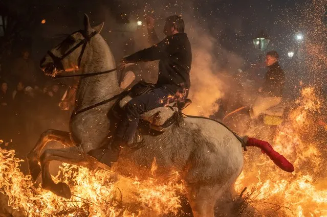A horse rider jumps over a bonfire on January 16, 2023 in San Bartolome de Pinares, Spain. Horse riders jump over bonfires during the traditional ritual in honor of San Antonio Abad (Saint Anthony the Abbot), patron saint of domestic animals known as Las Luminarias, which is meant to purify the animals with the smoke of the bonfires and protect them for the year to come. (Photo by Marcos del Mazo/Getty Images)
