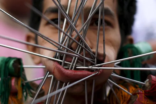 A devotee of the Chinese Samkong Shrine reacts after being pierced with spikes through his cheeks before a procession celebrating the annual vegetarian festival in Phuket, Thailand, October 16, 2015. (Photo by Jorge Silva/Reuters)