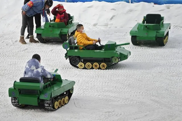 Children ride on toy tanks in the snow at a public park in Beijing, Thursday, January 19, 2023. (Photo by Andy Wong/AP Photo)