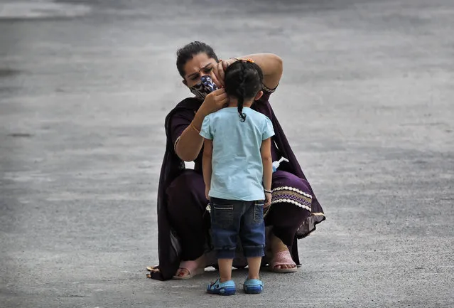 A woman fixes her daughter's face mask at a COVID-19 testing center in New Delhi, India, Saturday, October 3, 2020. India has crossed 100,000 confirmed COVID-19 deaths on Saturday, putting the country's toll at nearly 10% of the global fatalities and behind only the United States and Brazil. (Photo by Manish Swarup/AP Photo)