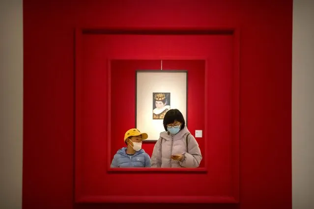 A woman and child wearing face masks walk through a gallery at the National Art Museum of China in Beijing, Wednesday, February 1, 2023. Visitors continue to flock to museums, historic sites, and tourist attractions in China's capital as the Lunar New Year holiday period winds down. (Photo by Mark Schiefelbein/AP Photo)