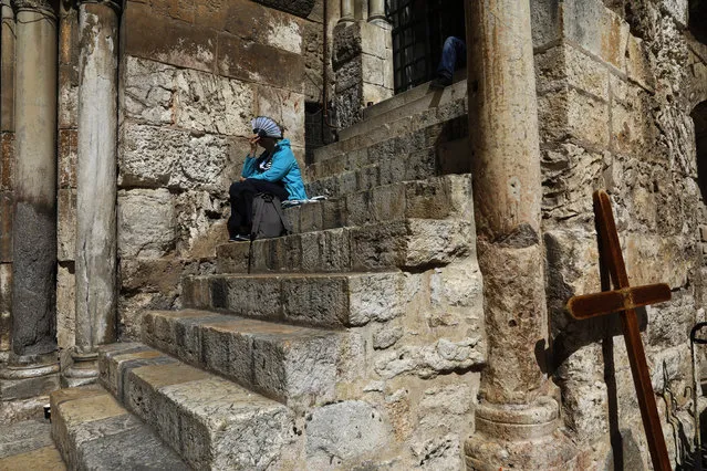 A pilgrim sits by the closed gate of the Church of the Holy Sepulchre in Jerusalem's Old City on February 25, 2018. Christian leaders took the rare step of closing the Church of the Holy Sepulchre, built at the site of Jesus's burial in Jerusalem, in protest at Israeli tax measures and a proposed property law. (Photo by Gali Tibbon/AFP Photo)