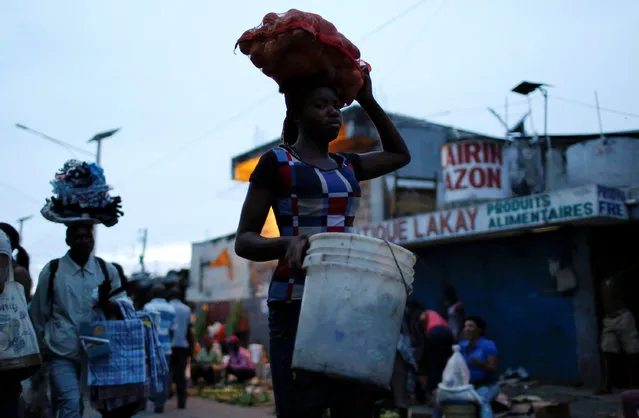 People carry their goods along a street market while Hurricane Matthew approaches in Port-au-Prince, Haiti, October 2, 2016. (Photo by Carlos Garcia Rawlins/Reuters)