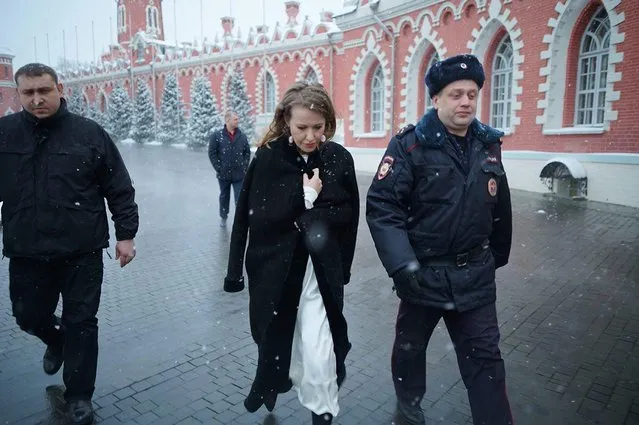 In this handout photo released by Russian presidential candidate Ksenia Sobchak's press service, Ksenia Sobchak, center, walks with a police officer after she was doused with water and knocked to the ground in an assault in Moscow, Russia, Sunday, March 4, 2018. The Sunday incident came several days after Sobchak threw water on nationalist presidential candidate Vladimir Zhirinovsky during a televised debate. (Photo by Campaign office of Ksenia Sobchak via AP Photo)