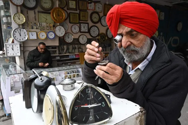 A clockmaker repairs a watch on his stall along a street in Amritsar on February 9, 2023. (Photo by Narinder Nanu/AFP Photo)