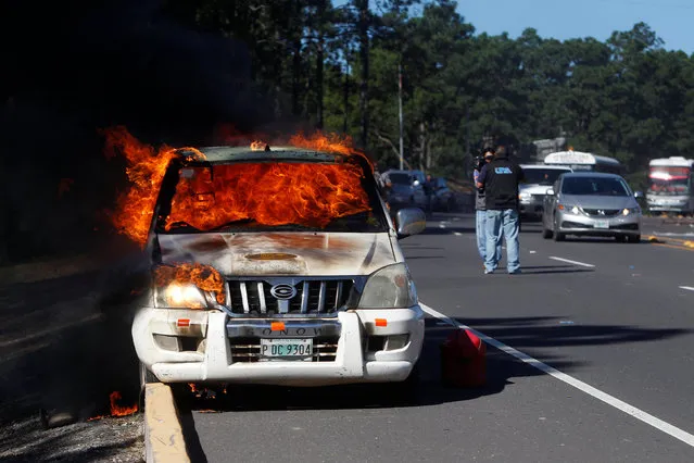A vehicle set ablaze by supporters of the Liberty and Refoundation party (LIBRE) is seen after clashes with police during a nationwide protest against the re-election bid of Honduras President Juan Orlando Hernandez for the 2017 election, in Zambrano, on the outskirts of Tegucigalpa, Honduras, October 3, 2016. (Photo by Jorge Cabrera/Reuters)