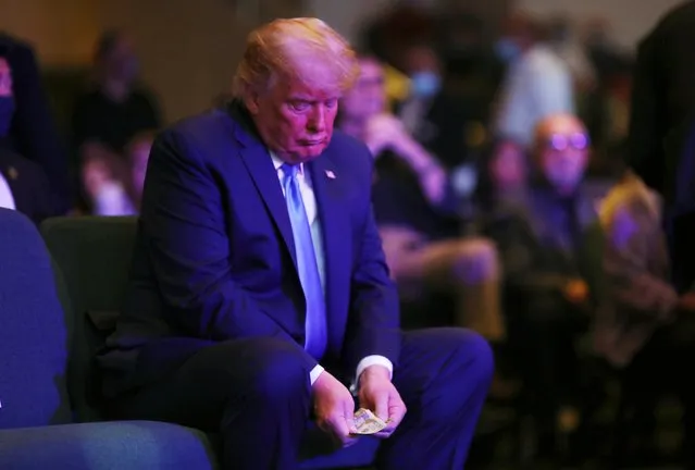 President Donald Trump counts money before donating it as he attends a service at the International Church of Las Vegas in Las Vegas, Nevada, October 18, 2020. (Photo by Carlos Barria/Reuters)
