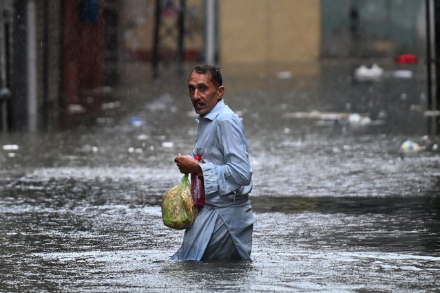 A man wades through a flooded street during heavy monsoon rains in Rawalpindi on July 17, 2025. Monsoon rains in Pakistan have been linked to more than 110 deaths including dozens of children since they arrived in late June, according to government figures released on July 14. (Photo by Aamir Qureshi/AFP Photo)