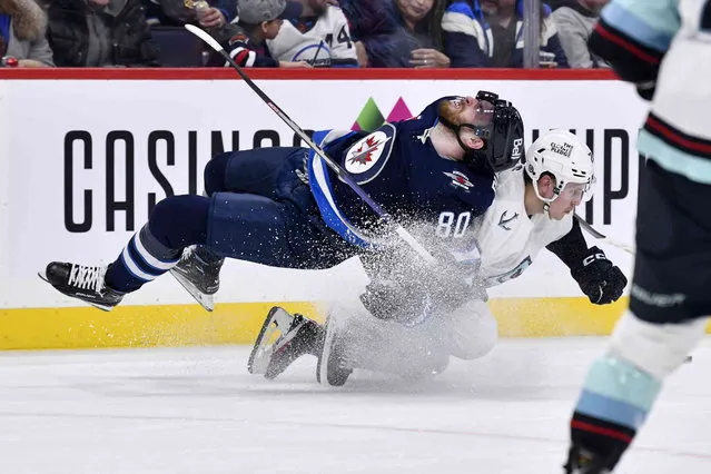 Seattle Kraken's Eeli Tolvanen (20) dumps Winnipeg Jets' Pierre-Luc Dubois (80) during the second period of an NHL game in Winnipeg, Manitoba on Tuesday February 14, 2023. (Photo by Fred Greenslade/The Canadian Press via AP Photo)