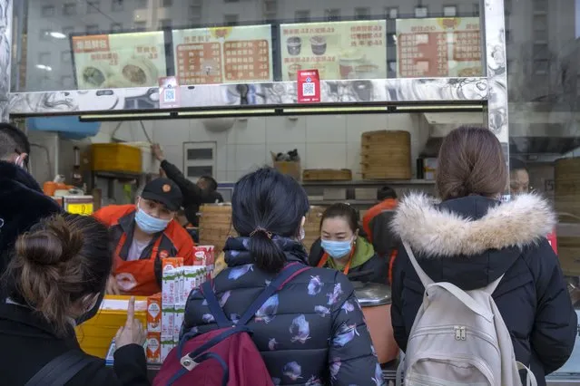 Commuters order food from a takeaway shop during the morning rush hour in Beijing, Monday, March 6, 2023.  Chinese economic officials expressed confidence Monday they can meet this year’s growth target of “around 5%” by generating 12 million new jobs and encouraging consumer spending following the end of anti-virus controls that kept millions of people at home. (Photo by Mark Schiefelbein/AP Photo)