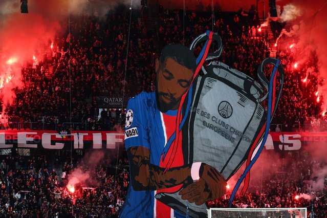 PSG supporters hold burning flares behind a giant tifo depicting Paris Saint-Germain's French defender #03 Presnel Kimpembe during a farewell ceremony to mark his leaving the club and heading to play for Qatar SC, after the French L1 football match between Paris Saint-Germain (PSG) and RC Lens at the Parc des Princes stadium in Paris, on September 14, 2025. France international defender Presnel Kimpembe has left Paris Saint-Germain to join Qatar Sports Club, the two teams announced on September 7, 2025. The 30-year-old centre-back has spent his whole career at PSG but was in the final year of his contract and had only made five appearances since suffering a ruptured Achilles tendon in February 2023. (Photo by Franck Fife/AFP Photo)