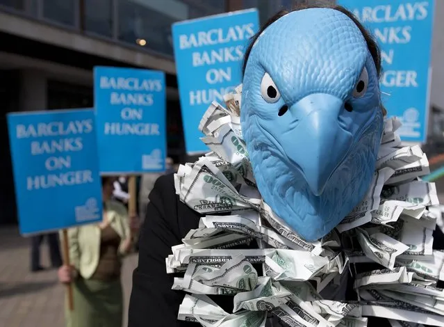 A protester, dressed to look like the Barclays Bank logo, demonstrates outside the Barclays Bank annual general meeting for shareholders, in central London,Thursday, April  25, 2013. Demonstrators from two groups posed for the media to draw attention to their campaigns for more bank regulation and for higher taxes on bank profits. (Photo by Alastair Grant/AP Photo)