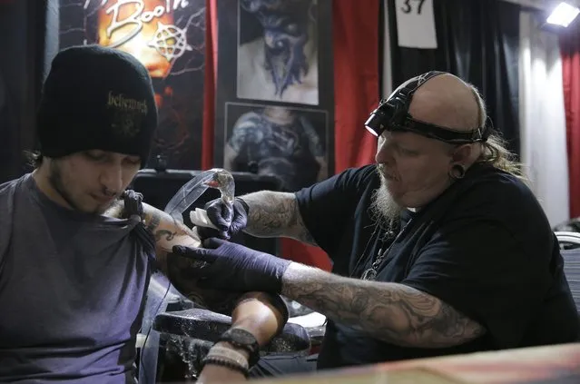 US tattoo artist Paul Booth (R) works on a customer during a tattoo convention in Bucharest, Romania, 15 October 2016. More than 100 tattoo artists from all over the world are participating at the seventh International Tattoo Convention Bucharest that runs until 16 October. (Photo by Robert Ghement/EPA)