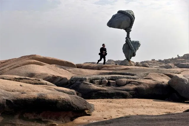 A man walks near a sculpture which according to its description symbolizes the unity of the peoples on both sides of the straits at the 68-nautical-mile scenic spot, one of mainland China's closest points to the island of Taiwan, on Pingtan Island, Fujian province, China on April 8, 2023. (Photo by Thomas Peter/Reuters)