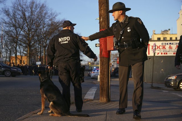 An Ohio State Highway patrol officer (R) puts his hand on the shoulder of an NYPD Canine unite officer upon arriving for the funeral of NYPD officer Rafael Ramos, at Christ Tabernacle Church in Queens, New York December 27, 2014. Thousands of police and other mourners were expected to fill the church and surrounding streets for the funeral Saturday of Ramos, one of two police officers ambushed by a gunman who said he was avenging the killing of unarmed black men by police. (Photo by Shannon Stapleton/Reuters)