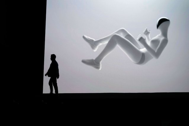He Xiaopeng, Chairman and CEO of XPENG walks past a video showing the company's next generation IRON robot during the XPENG AI Day held at the company headquarters in Guangzhou in southern China's Guangdong province, Wednesday, November 5, 2025. (Photo by Ng Han Guan/AP Photo)