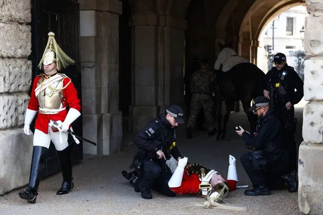 A member of the Household Cavalry lies on the ground after falling from his horse during the Changing of the Guard ceremony in London, Britain on March 28, 2022. (Photo by Tom Nicholson/Reuters)