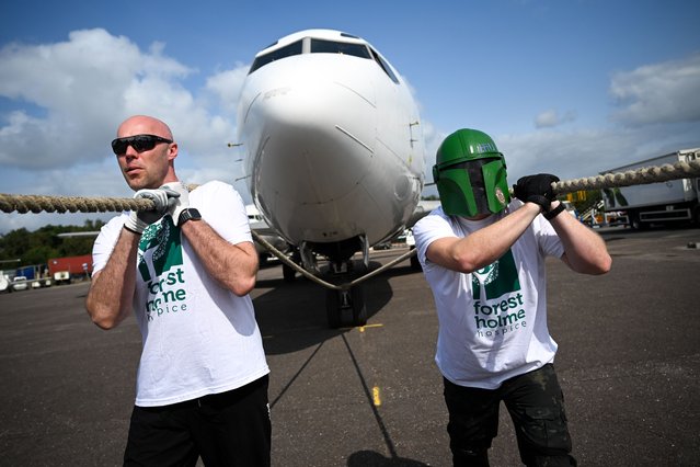 A man dressed as a Mandalorian from Star Wars takes part with his team as they raise money for their chosen charities taking part in the Dorset Plane Pull, hosted by European Skybus Ltd, on August 26, 2024 in Bournemouth, England. Founded in 2009 in memory of family members who passed away from Motor Neurone Disease and friend, John Thornton, who was killed while serving as a Royal Marine in Afghanistan, Dorset Plane Pull has raised over £300,000 for 56 charities. Teams of 20 people enter to pull a Boeing 737 weighing in at 35,000 Kg a distance of 50 metres to raise money for charity. (Photo by Finnbarr Webster/Getty Images)
