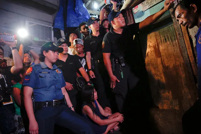 Funeral parlour workers, policemen, reporters and the relatives of a person who was killed, wait for investigation to be done outside a house in Manila, Philippines early November 1, 2016. (Photo by Damir Sagolj/Reuters)