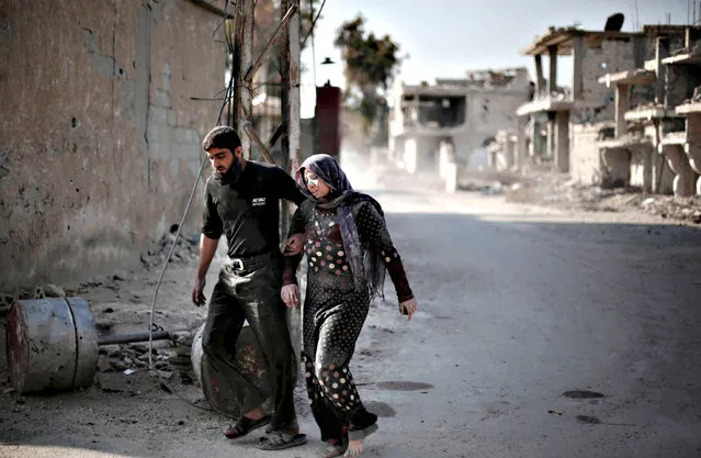 A Syrian man escorts his injured wife following reported air strikes by regime forces on the town of al-Nashabiyah in the eastern Ghouta region, a rebel stronghold east of the capital Damascus, on December 14, 2015. (Photo by Amer Almohibany/AFP Photo)