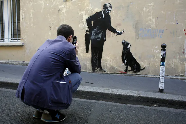 A man takes a picture of a graffiti believed to be attributed to street artist Banksy, in Paris, Monday, June 25, 2018. Seven works attributed to the graffiti artist have been discovered in recent days, including one near a former center for migrants at the city's northern edge, according to the art website Artistikrezo. (Photo by Thibault Camus/AP Photo)