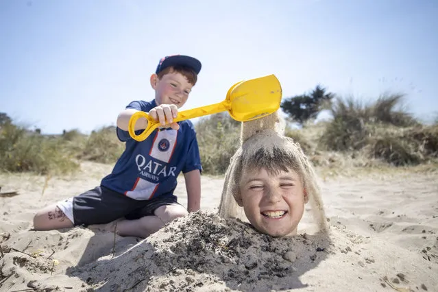 Harry O‘Mahony (aged 9) gets buried in the sand by his friend Danny Maher (aged 8) on Burrow Beach, Sutton, Dublin on June 5, 2023. (Photo by Tom Honan for The Irish Times)