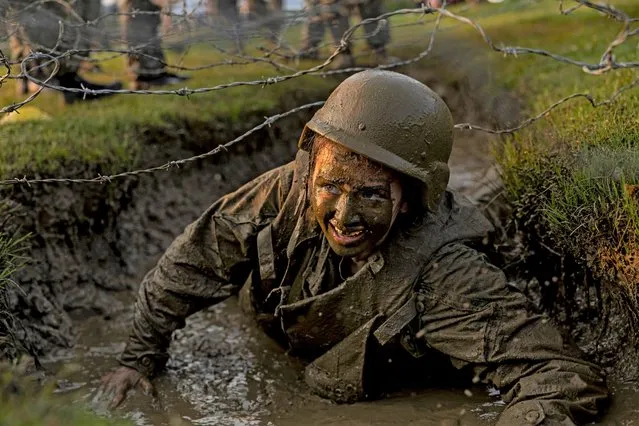 A Naval Academy Plebe crawls through a mud-filled trench while taking part in the “Wet and Sandy” portion of the annual Sea Trials at the U.S. Naval Academy on May 16, 2023 in Annapolis, Maryland. For the annual Sea Trials, the Naval Academy freshman class took part in a 14-hour series of rigorous exercises starting in the early hours of the morning as part of the culmination of their “Plebe” year at the academy. (Photo by Anna Moneymaker/Getty Images)