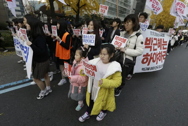 South Korean children march with high school students during a rally calling for South Korean President Park Geun-hye to step down in Seoul, South Korea, Saturday, November 19, 2016. For the fourth straight weekend, masses of South Koreans were expected to descend on major avenues in downtown Seoul demanding an end to the presidency of Park, who prosecutors plan to question soon over an explosive political scandal. The letters read “Park Geun-hye should step down”. (Photo by Ahn Young-joon/AP Photo)