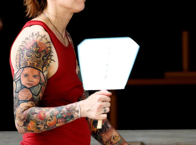 A foreign tourist with tattoos on her arms uses a fan at Meiji Shrine during a heatwave in Tokyo, Japan July 25, 2018. (Photo by Kim Kyung-Hoon/Reuters)