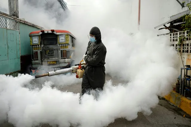 A worker in a hazmat suit disinfects a street as a preventive measure against the spread of coronavirus disease (COVID-19) at a village in Manila, Philippines, March 19, 2021. (Photo by Lisa Marie David/Reuters)