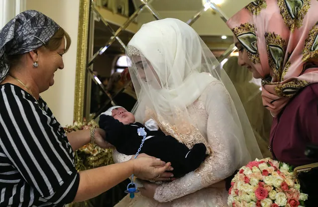The bride with a baby of her relative during a wedding celebration in Chechen capital Grozny, Russia on November 24, 2016. (Photo by Valery Sharifulin/TASS)