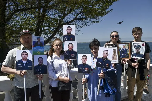 Relatives of servicemen who died during the Russian Special military operation in Donbas pose for a photo holding portraits of Russian soldiers killed during a fighting in Ukraine, after attending the Immortal Regiment march through a street marking the 77th anniversary of the end of World War II, in Sevastopol, Crimea, May 9, 2022. Moscow has not given a casualty count since it said some 1,300 troops were killed in the first month of fighting, but Western officials have said that was just a fraction of real losses. (Photo by AP Photo/Stringer)