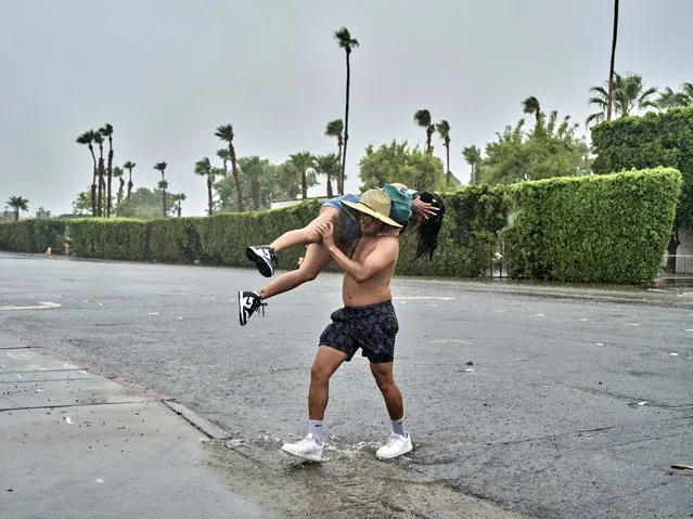 People cross a flooded street during a rainstorm as Tropical Storm Hilary arrives Palm Springs, California on August 20, 2023. Southern California is under a tropical storm warning which could bring heavy rains, high winds and flooding. (Photo by Philip Cheung for The Washington Post)