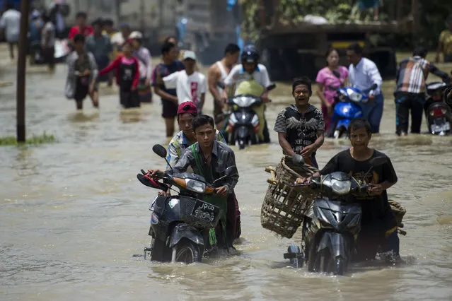 Residents make their way through a flooded road in Taungnu township of Bago region in Myanmar on August 31, 2018. (Photo by Ye Aung Thu/AFP Photo)