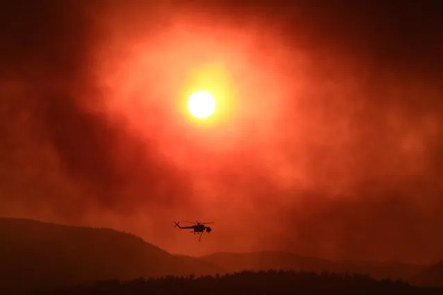 A helicopter flies over as wildfire rages near Alexandroupoli, northern Greece, on August 21, 2023. The European Union announced it was deploying two Cyprus-based fire-fighting aircraft and a Romanian fire-fighting team via the bloc's civil protection mechanism, as wildfires rage uncontrolled in Greece for a third day. (Photo by Sakis Mitrolidis/AFP Photo)