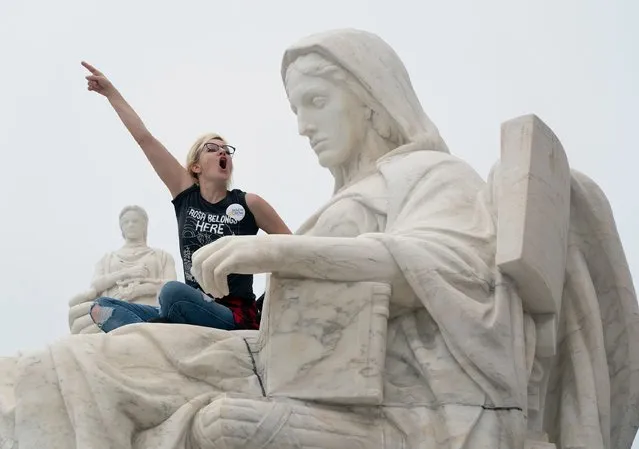 A protester demonstrates on a statue at the Supreme Court in Washington, DC in opposition to the Senate confirmation of Brett Kavanaugh to the court, October 6, 2018. (Photo by Chris Kleponis/AFP Photo)