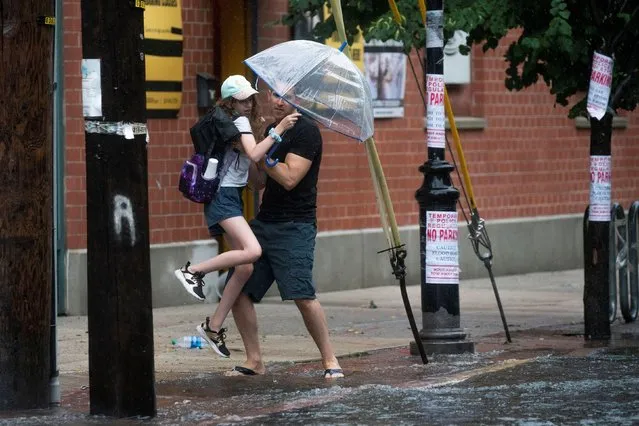 People make their way on a flooded street as Tropical Storm Elsa passes through Hoboken, New Jersey, U.S., July 9, 2021. (Photo by Eduardo Munoz/Reuters)