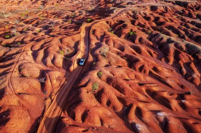 Aerial view showing a car riding along a dirt road in the Desert of Gilbues, in Gilbues, in the northeastern state of Piaui, Brazil, taken on September 30, 2023. Gilbues is Brazil's worst desertification hotspot, where a parched, canyon-pocked landscape is swallowing up farms and residences, claiming an area bigger than New York City. Experts say the phenomenon is caused by rampant erosion of the region's naturally fragile soil, exacerbated by deforestation, reckless development and probably climate change. (Photo by Nelson Almeida/AFP Photo)