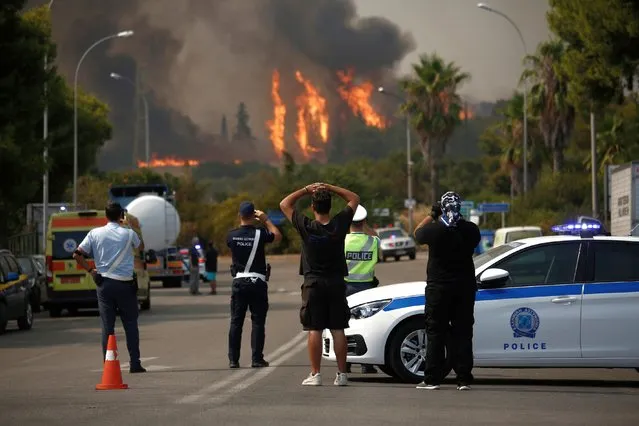 Citizens and police officers watch the wildfire burning at Varybobi, northeastern suburb of Athens, Greece, 03 August 2021. (Photo by Yannis Kolesidis/EPA/EFE)