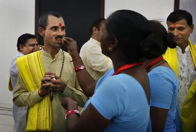 Dalit women of India's outcast community once known as untouchables, in blue saree, offer sweets to upper cast Hindu priests at a function to mark the eve of the birth anniversary of Bhim Rao Ambedkar in New Delhi, India, Monday, April 13, 2015. Ambedkar, an untouchable, or dalit, and a prominent Indian freedom fighter, was the chief architect of the Indian Constitution, which outlawed discrimination based on caste. (Photo by Manish Swarup/AP Photo)