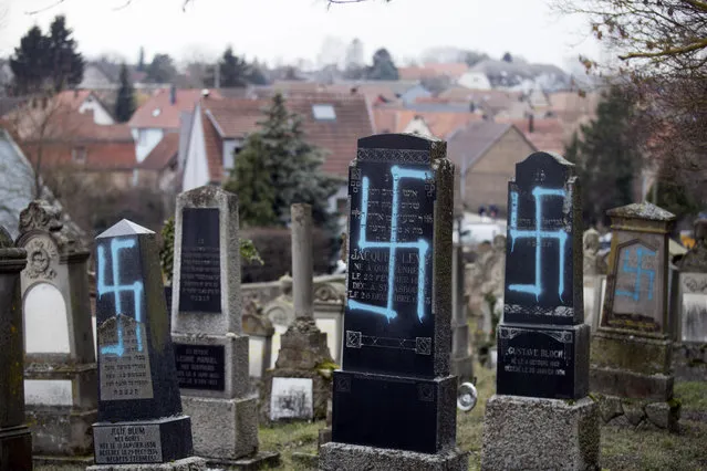 Vandalized tombs with tagged swastikas are pictured in the Jewish cemetery of Quatzenheim, eastern France, Tuesday, February 19, 2019. Marches and gatherings against anti-Semitism are taking place across France following a series of anti-Semitic acts that shocked the country. (Photo by Jean-Francois Badias/AP Photo)
