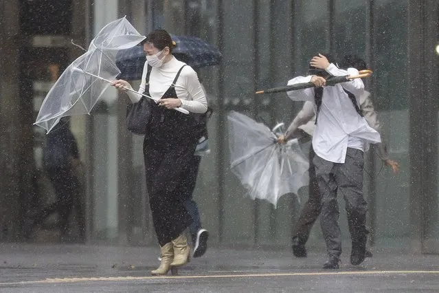 People struggle with rain and strong wind as Typhoon Mindulle travels off the coast of Japan Friday, October 1, 2021, in Tokyo. A powerful typhoon is pounding Japan and some of its eastern islands with gusts and downpours of rain, grounding some domestic flights and halting trains. (Photo by Kiichiro Sato/AP Photo)
