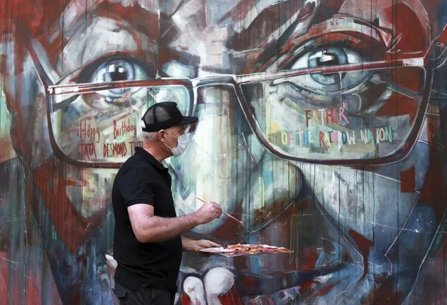 A wall mural, depicting Anglican Archbishop Emeritus, Desmond Tutu, is restored by the artist Brian Rolfe after it was defaced, in Cape Town, South Africa Thursday October 7, 2021. As South Africa's anti-apartheid icon, Tutu turns 90, recent racist graffiti on the wall mural portrait highlights the continuing relevance of his work for equality. (Photo by Nardus Engelbrecht/AP Photo)