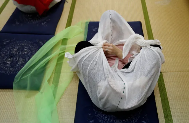 A woman performs Otonamaki, which translates as “adult wrapping”, a new form of therapy where people are wrapped in large swaddling cloth to alleviate posture problems and stiffness, at a session in Asaka, Saitama prefecture, Japan, February 4, 2017. (Photo by Toru Hanai/Reuters)